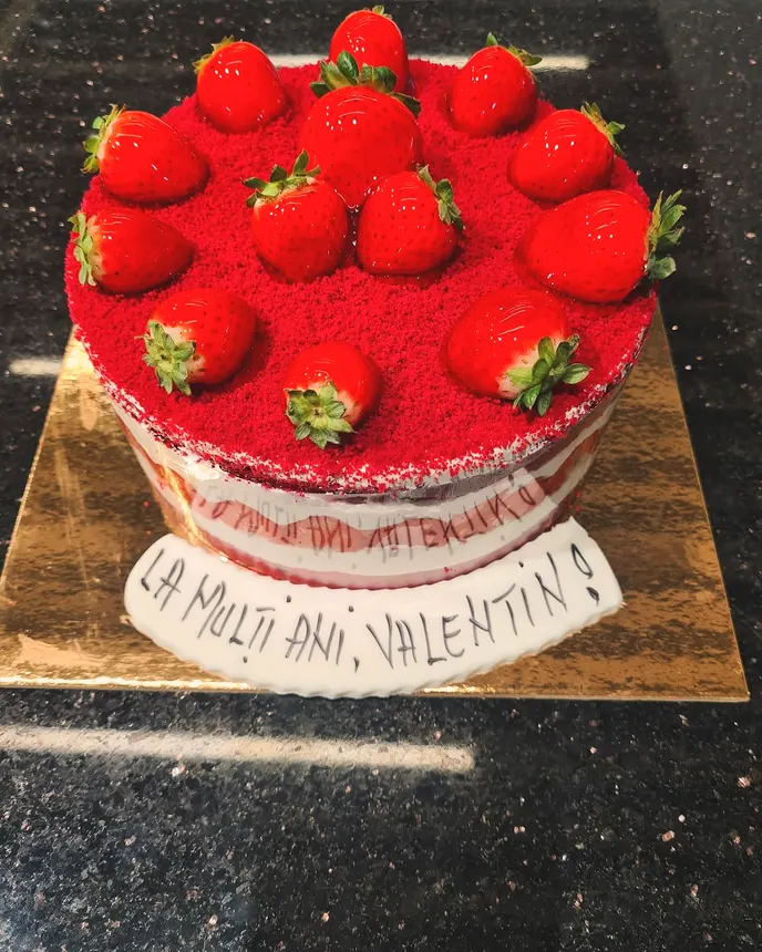 Tort cu căpșuni întregi deasupra, pe blat roșu de red velvet
