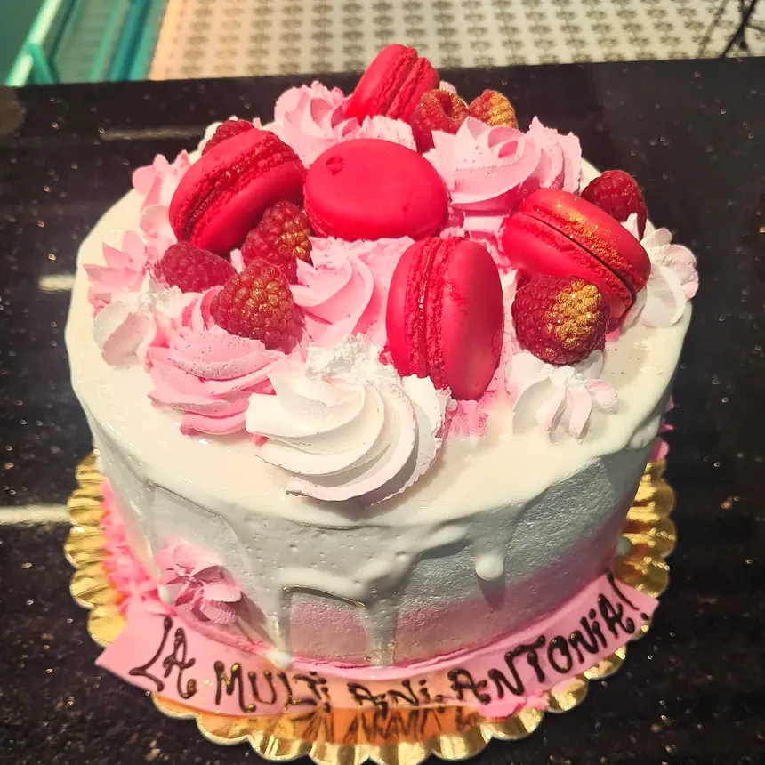 Tort cu macarons roz, zmeură și rozete de cremă