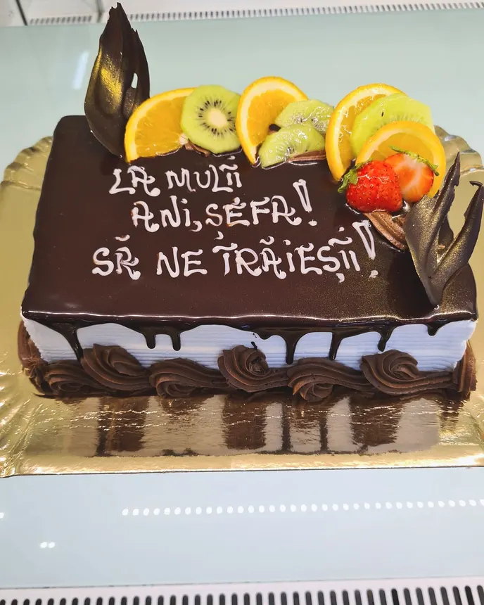 Tort dreptunghiular cu glazură de ciocolată și felii de fructe proaspete