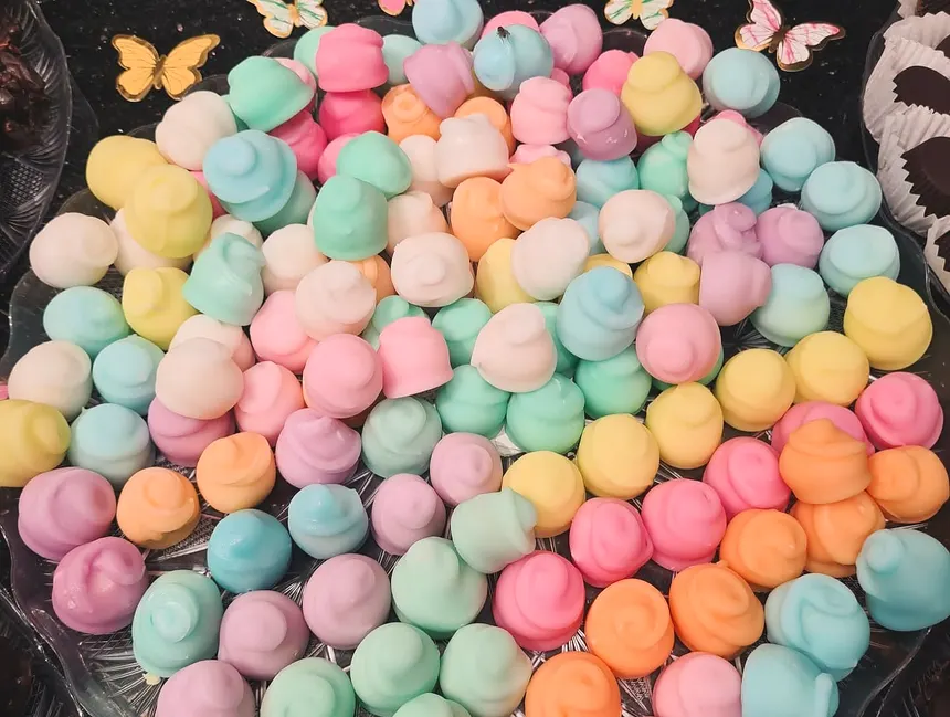 Mini-prăjituri colorate în pastel, așezate una lângă alta pe un platou