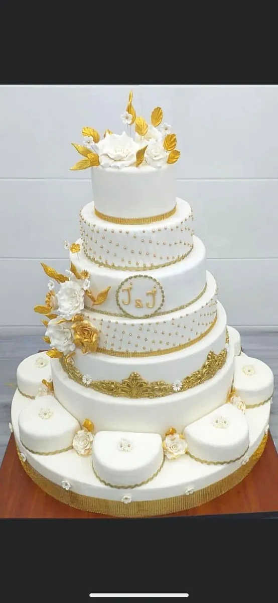 Tort de nuntă cu cinci etaje, alb cu perle și decoruri aurii, cu monograma mirilor