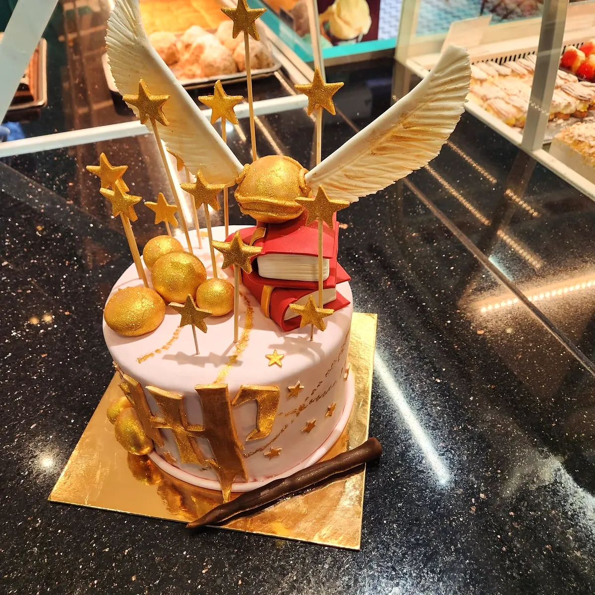 Tort roz cu tema Harry Potter, cu hoinarul de aur din zahăr și baghete de ciocolată