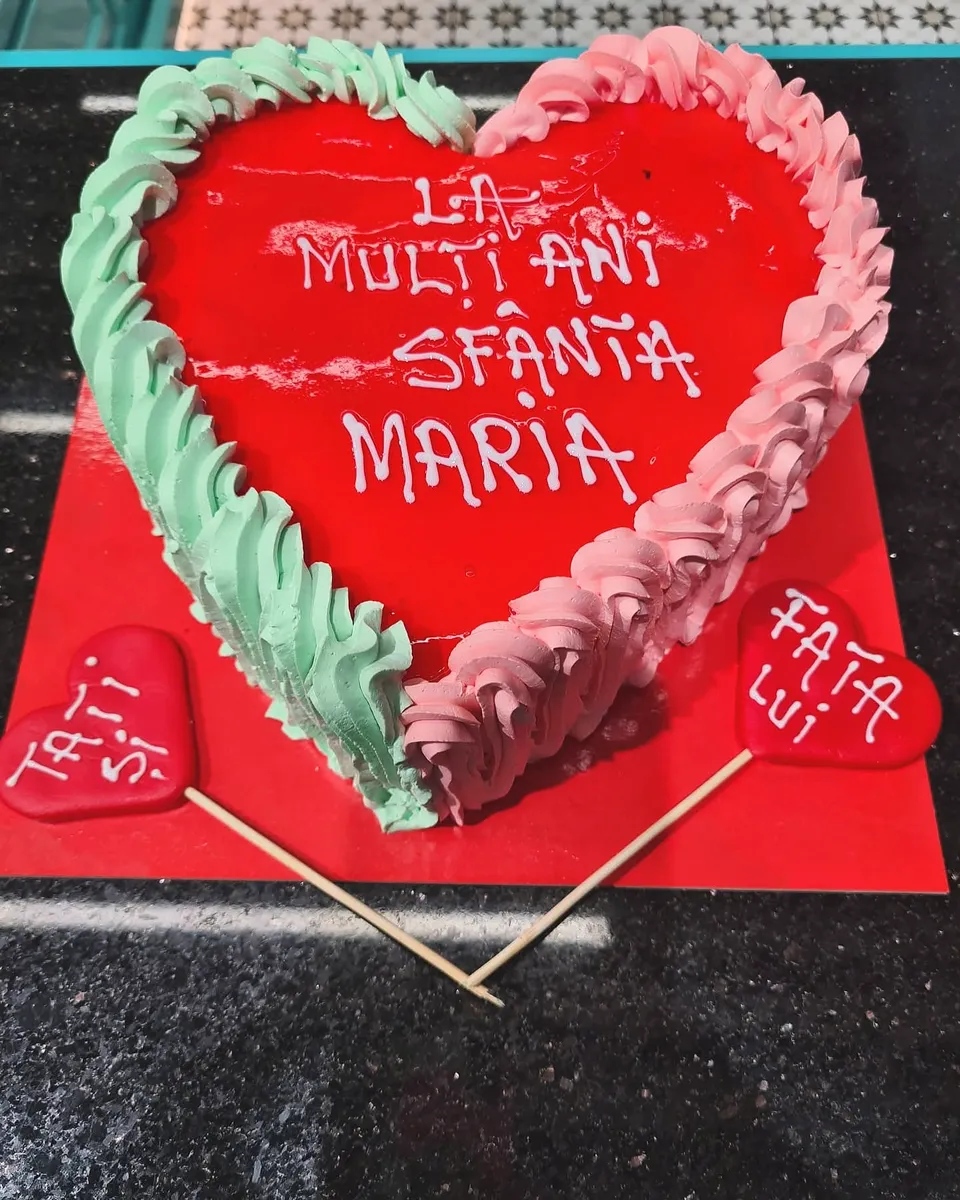 Tort inimă roșu cu decor verde și alb, cu mesajul Sfânta Maria scris pe glazură